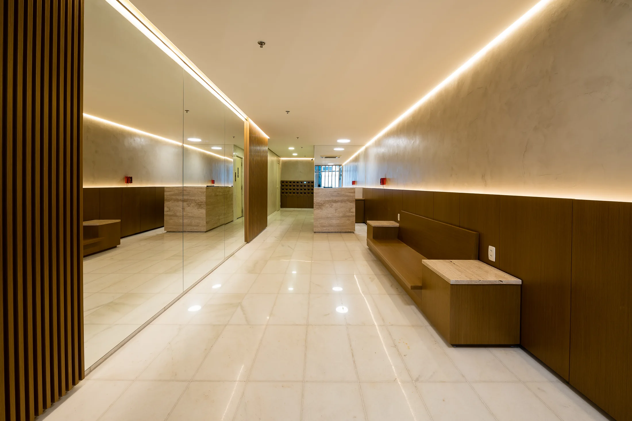 Condomínio Residencial, Leblon — resultado final 2, hall com banco embutido em madeira, espelho e piso de mármore claro